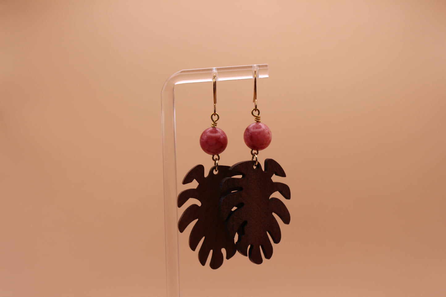 walnut monstera earrings with pink beads on a beige background